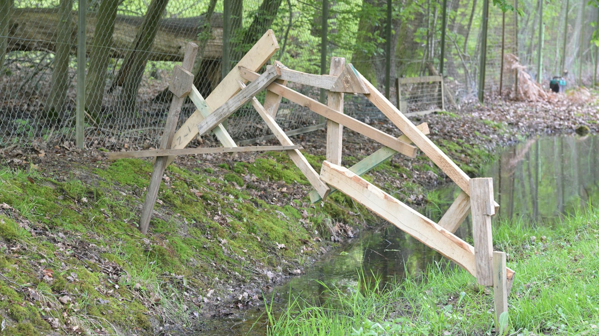 Mit einer Brücke bringt Künstlerin Helli Hecht im Skulpturengarten Brander Straße in Rösrath die Elemente Holz und Wasser zusammen.