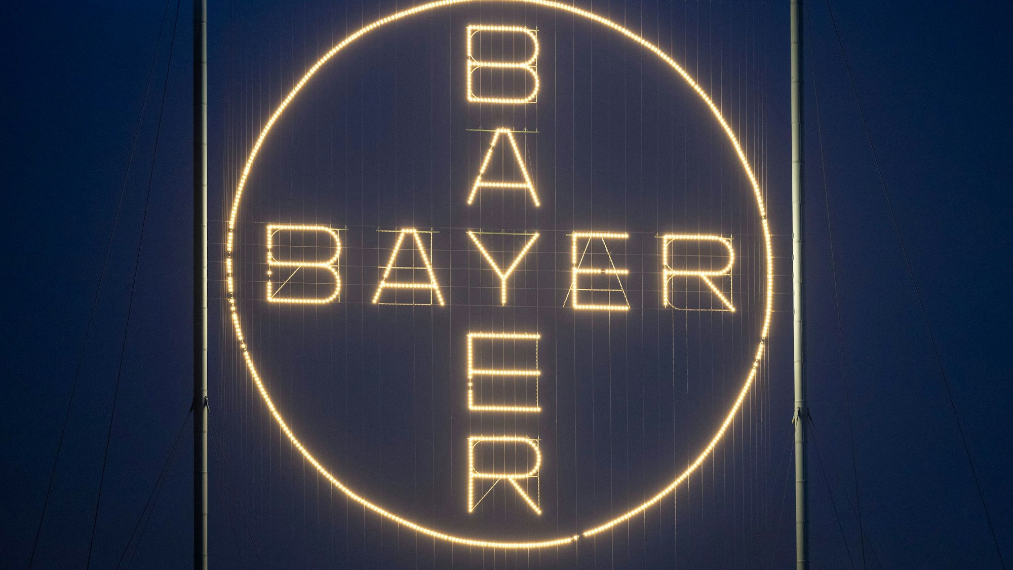 ARCHIV - 20.11.2023, Nrw, Köln: Das Bayer Kreuz, das Logo des Unternehmens, leuchtet auf dem Werksgelände von Bayer in Leverkusen. In ihrer Kritik an gentechnisch verändertem Saatgut und an dem Unkrautvernichter Glyphosat setzen Menschenrechtler den Agrarchemie-Konzern Bayer etwas unter Druck. (zu dpa: «Wegen Glyphosat: Menschenrechtler beschweren sich bei OECD über Bayer») Foto: Thomas Banneyer/dpa +++ dpa-Bildfunk +++