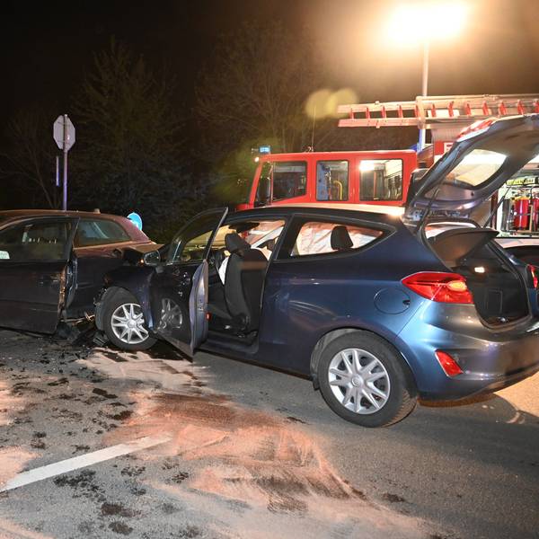 Zwei beschädigte Autos. Im Hintergrund ein Einsatzfahrzeug der Feuerwehr.
