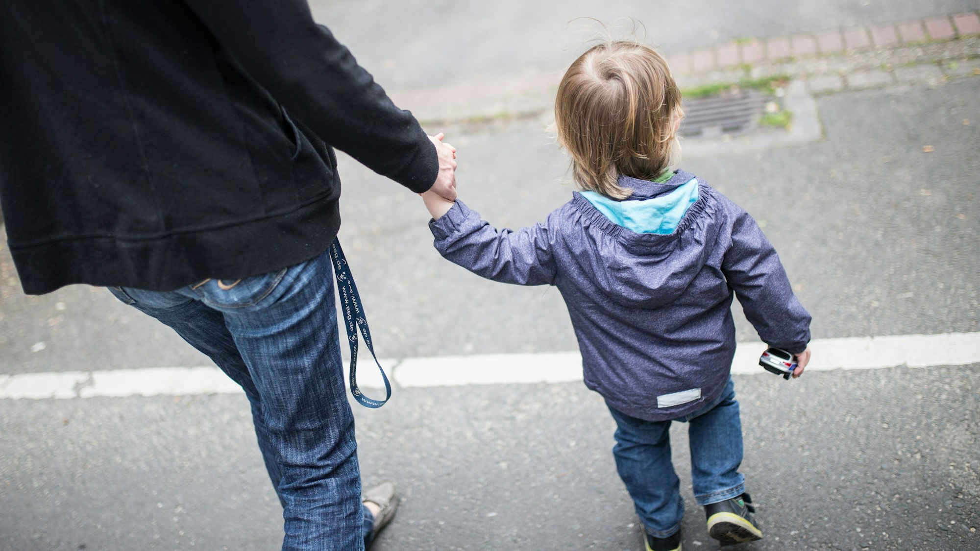 Eine Mutter hält ihren Sohn an der Hand.