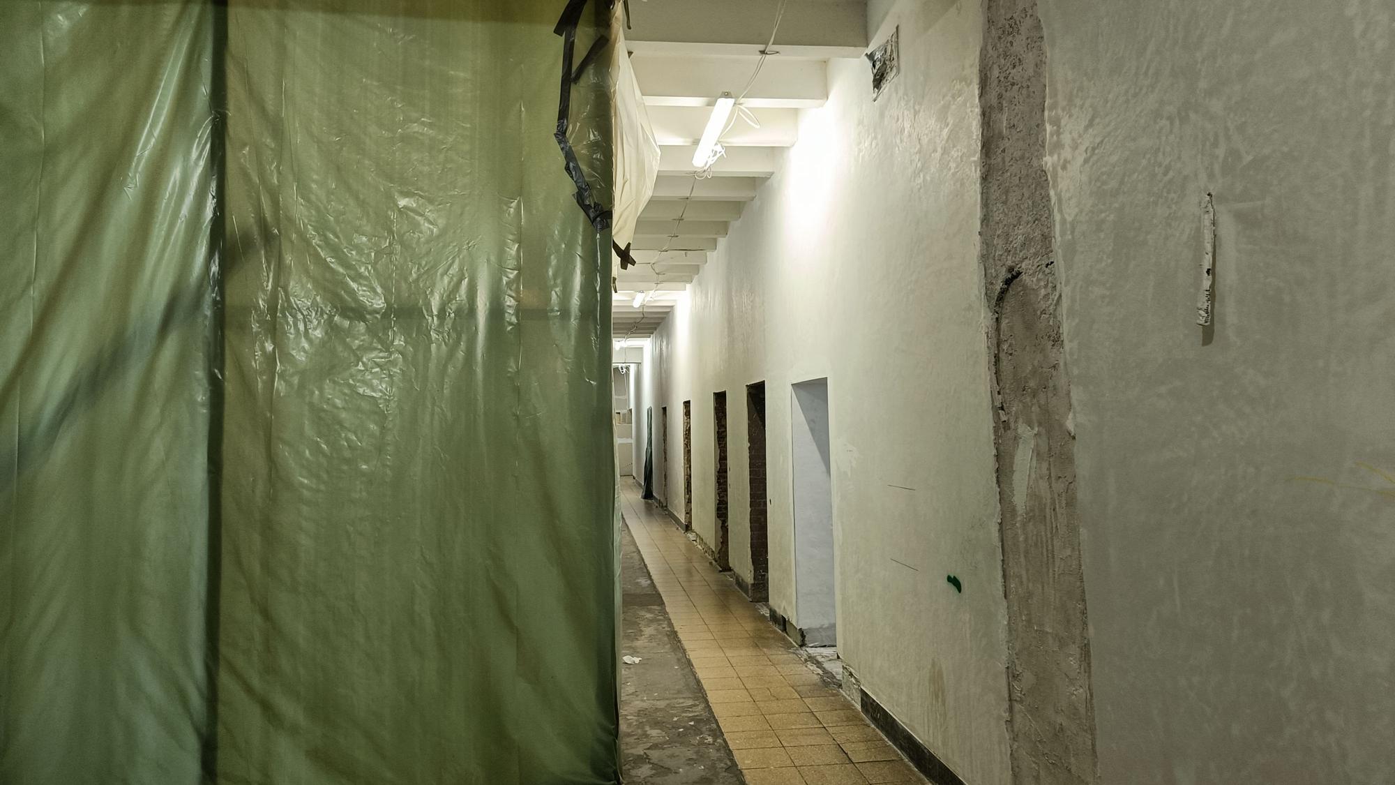 Ein gang im hauptgebäude, der Planen zeigt sowie bröckelnde Wände