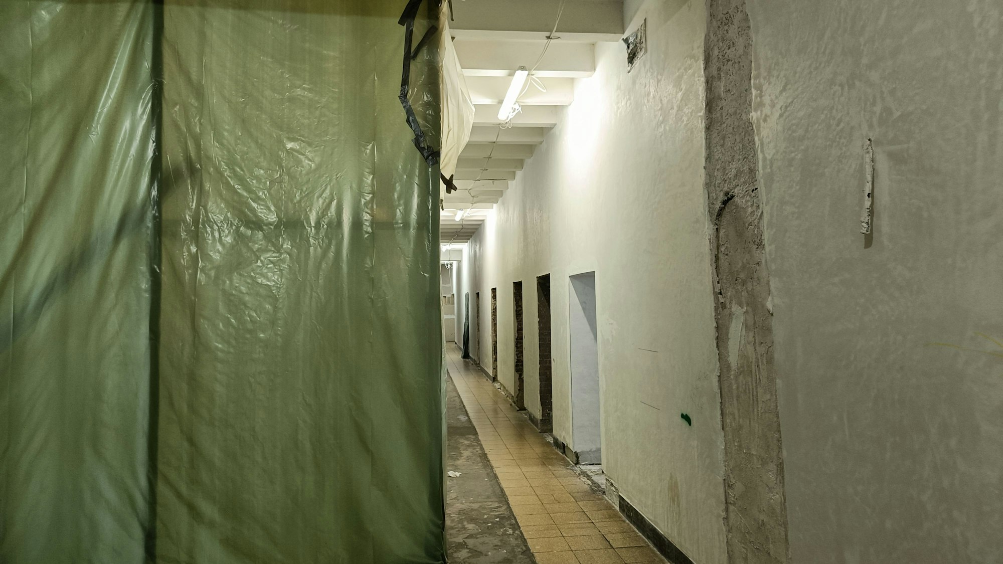 Ein gang im hauptgebäude, der Planen zeigt sowie bröckelnde Wände