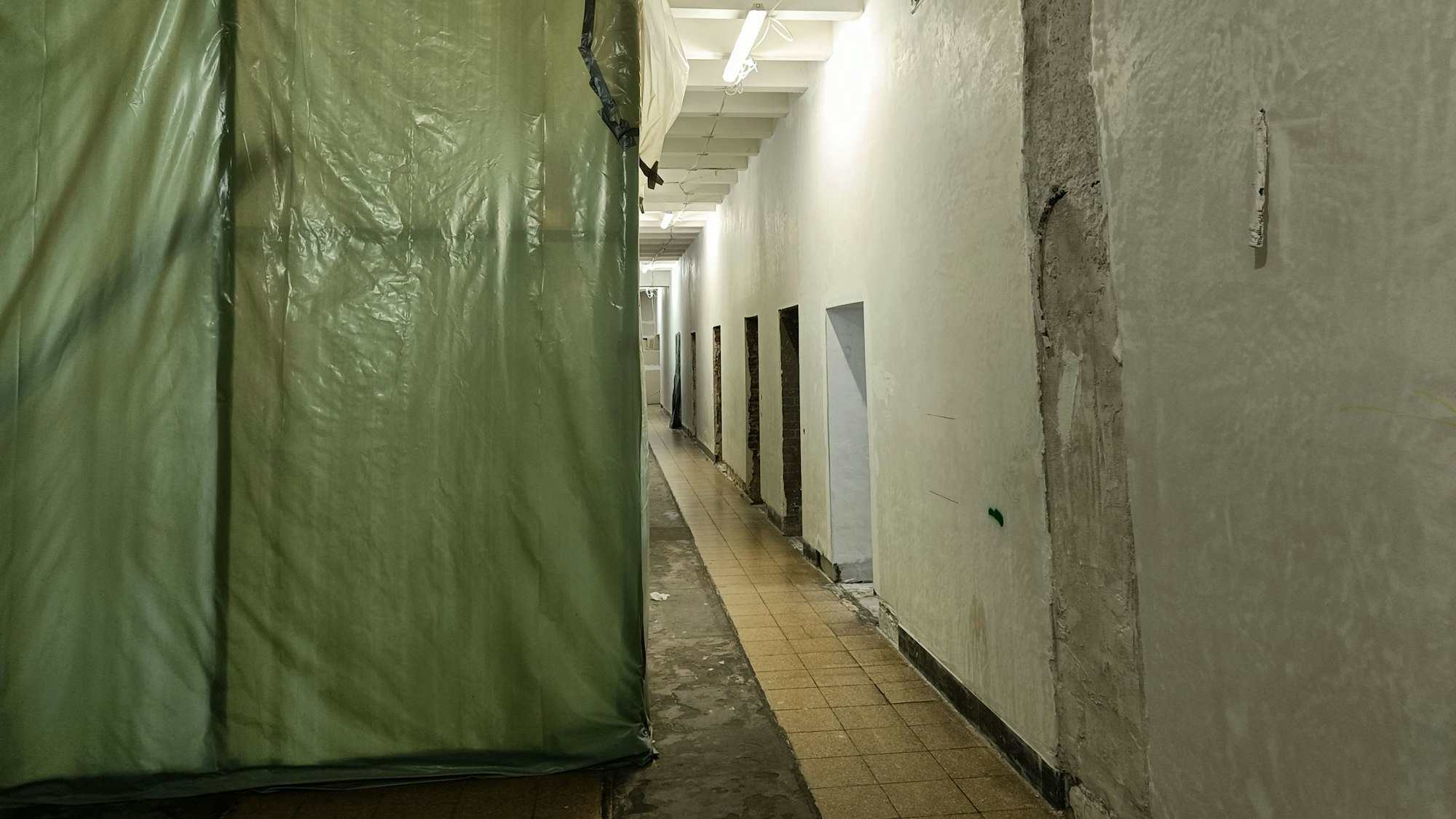 Der linke Teil eines Korridors ist mit grüner Plane abgedeckt.