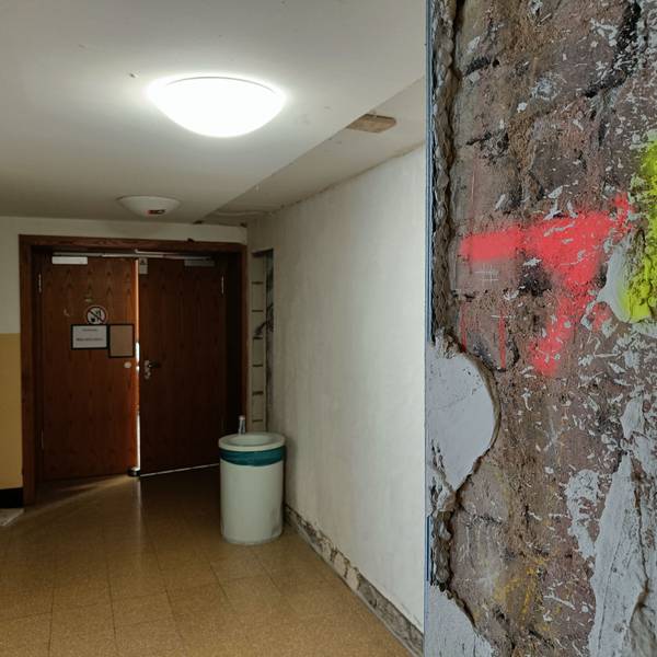 An einer Säule vor einem Hörsaal ist großflächig der Putz abgebröckelt.