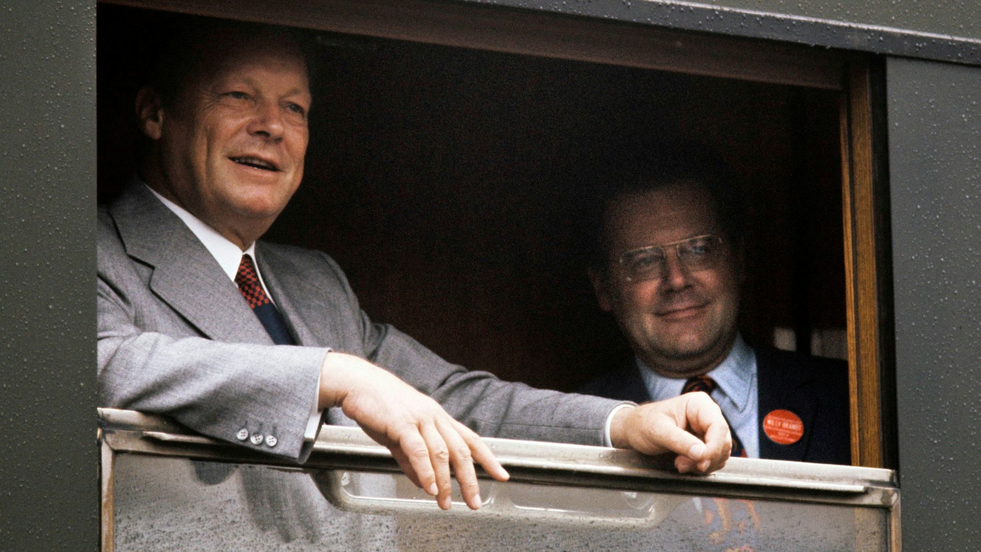 Willy Brandt steht am geöffneten Fenster eines Zuges, auf dem Bild rechts steht sein Referent Günter Guillaume. Beide blicken aus dem Fenster.