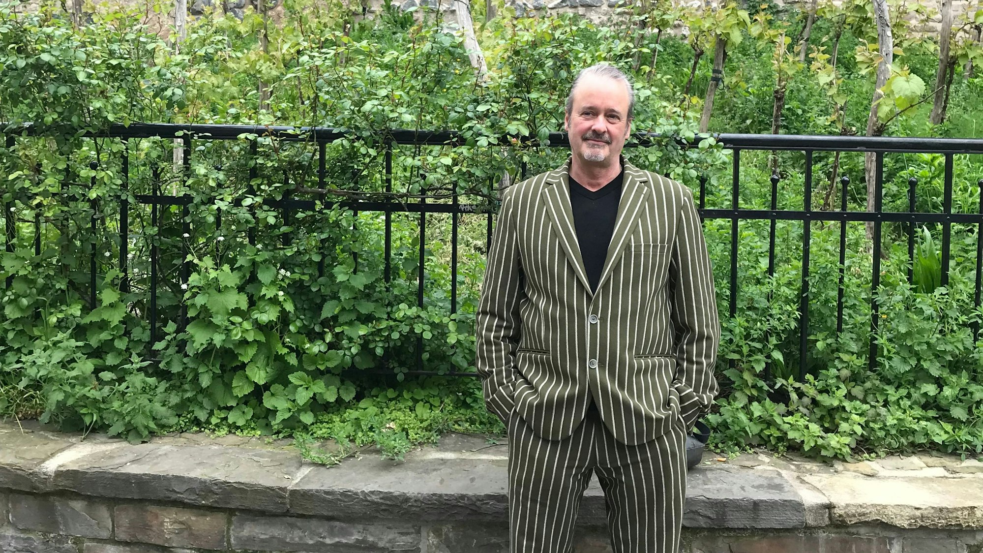 Bernd Imgrund steht vor der Severinstorburg in einem gestreiften Anzug.