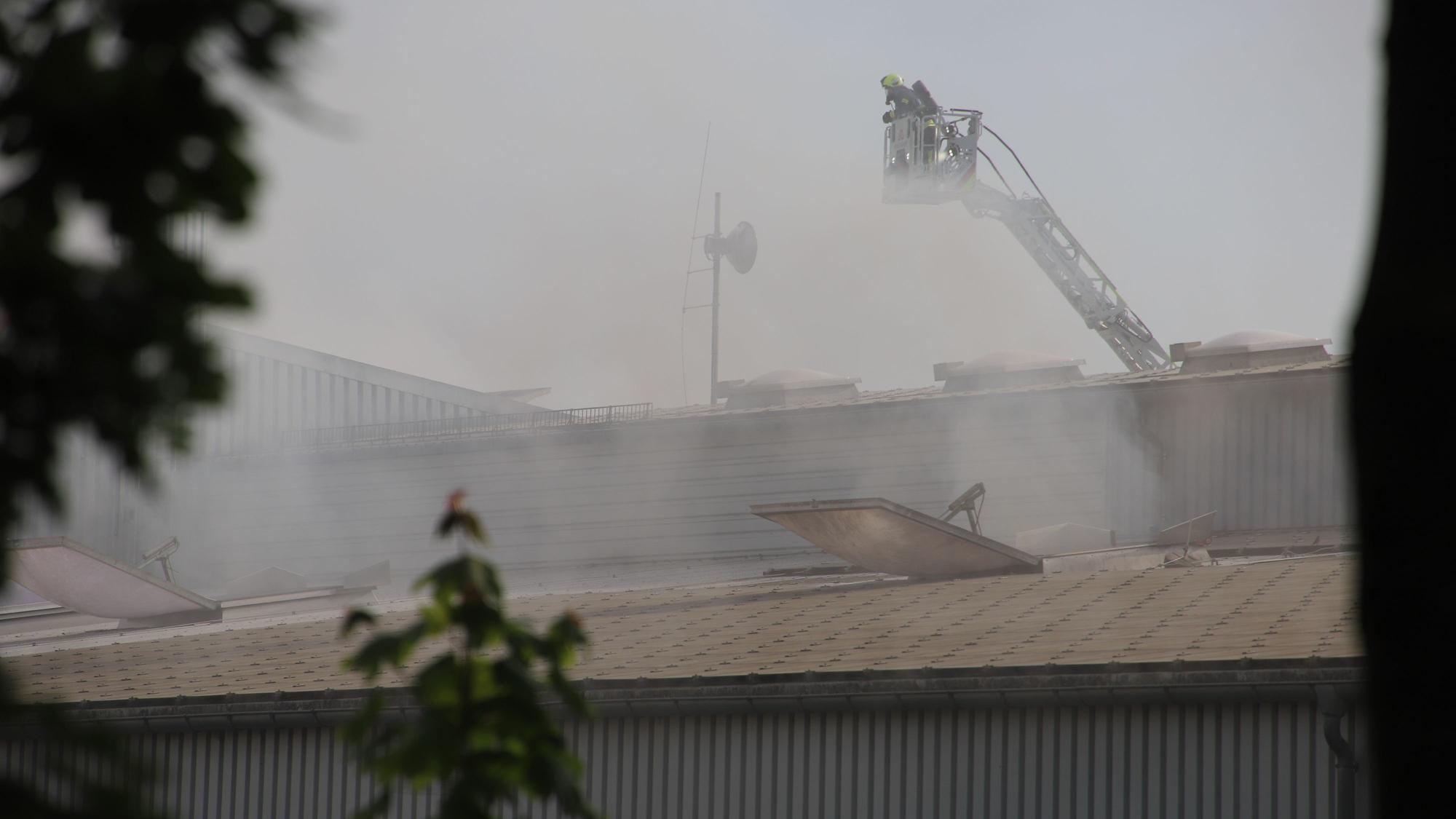 Dichter Rauch stieg aus den Klappen der Halle, von der Drehleiter aus löschten Feuerwehrleute.
