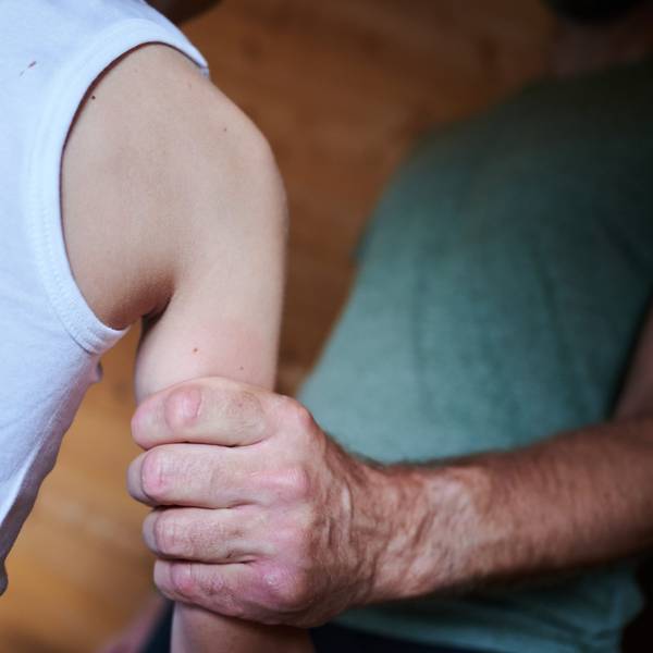 Ein Mann hält ein Kind fest am Arm (gestellte Szene).