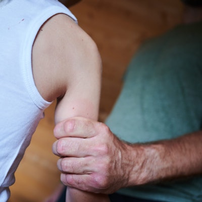 Ein Mann hält ein Kind fest am Arm (gestellte Szene).