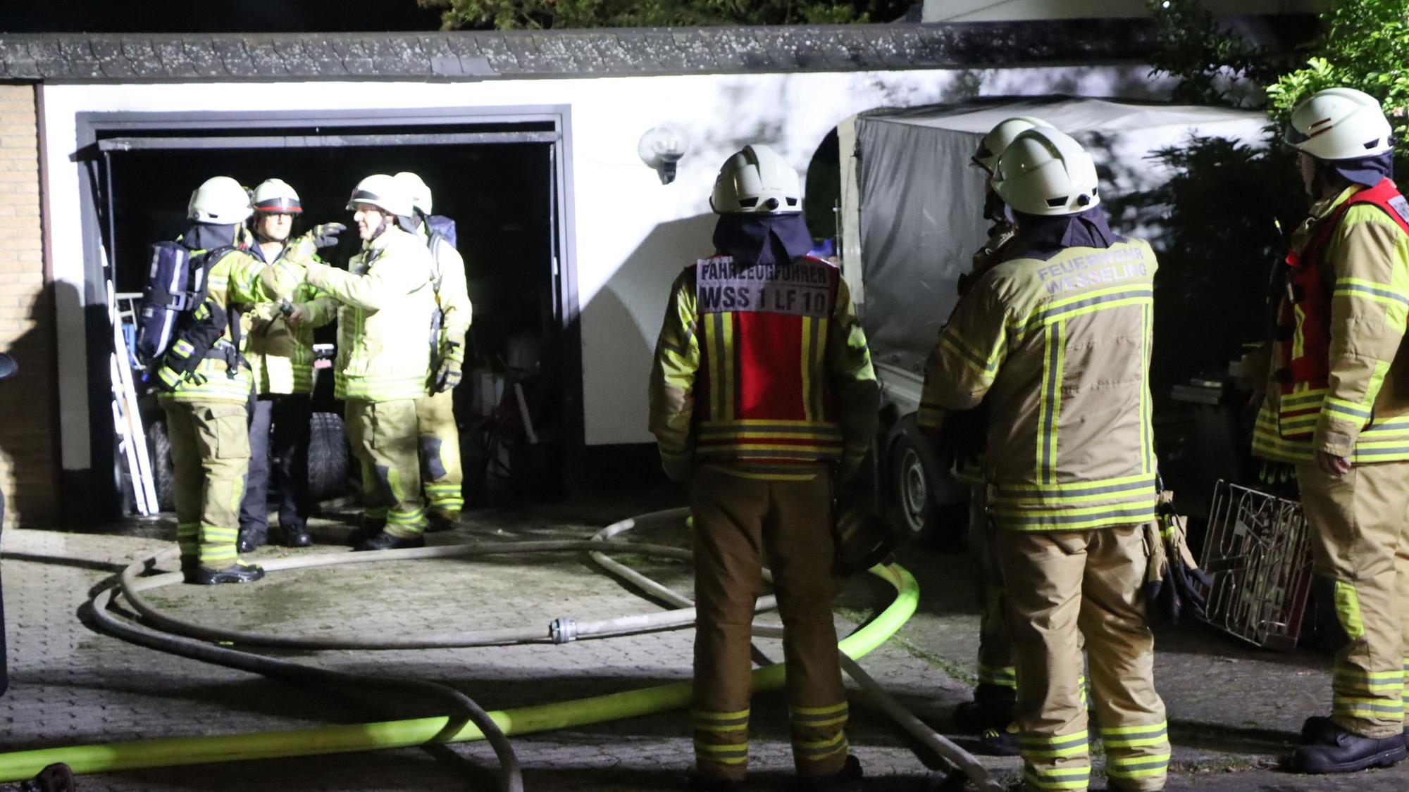 Feuerwehrleute stehen vor der ausgebrannten Garage.