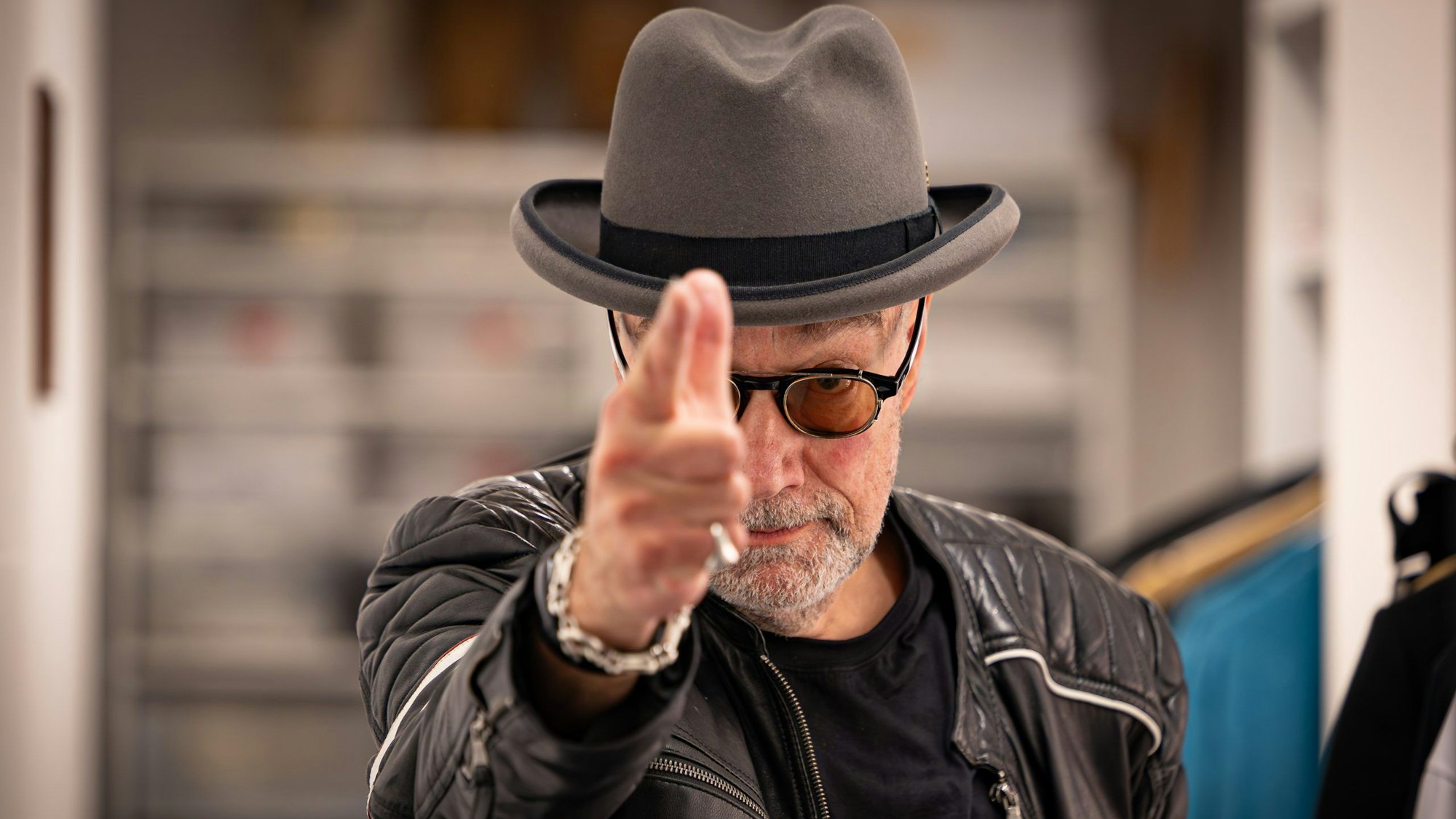 Mann mit Hut zeigt Richtung Kamera.