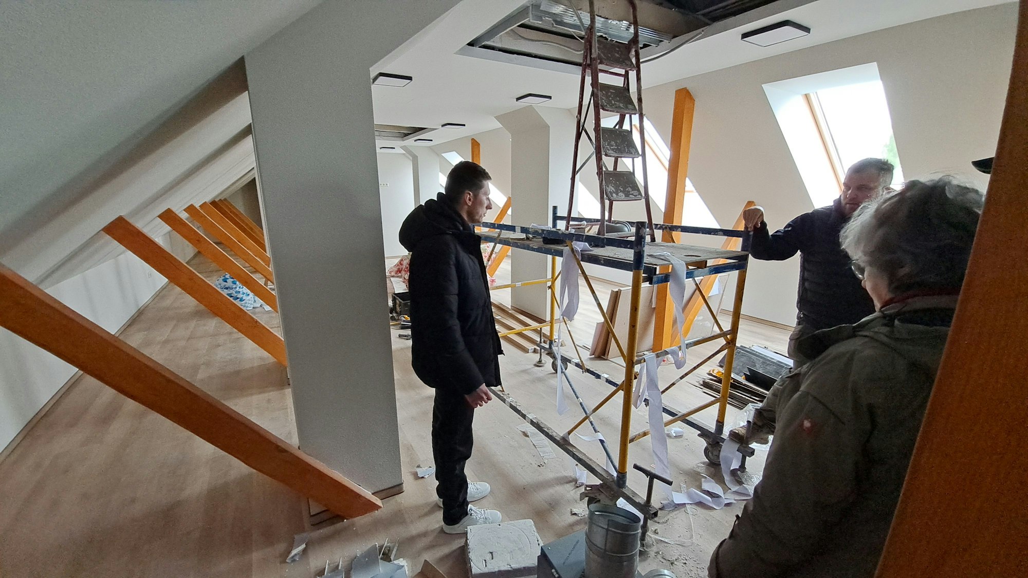 Männer stehen in einem noch mit Gerüsten vollgestellten Dachspeicherraum des neuen Traumazentrums im Süden der Ukraine.