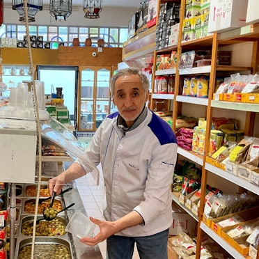 Mann schöpft im Geschäft aus einer Oliven-Auswahl