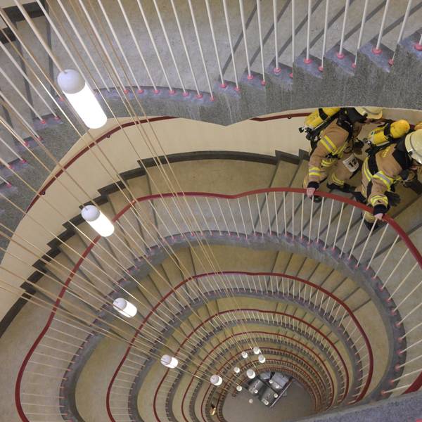 Blick von oben hinunter in ein Treppenhaus, das oval geschwungen über acht Etagen nach unten verläuft.
