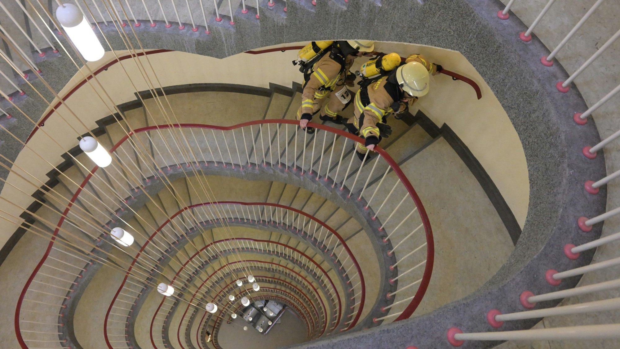 Blick von oben hinunter in ein Treppenhaus, das oval geschwungen über acht Etagen nach unten verläuft.