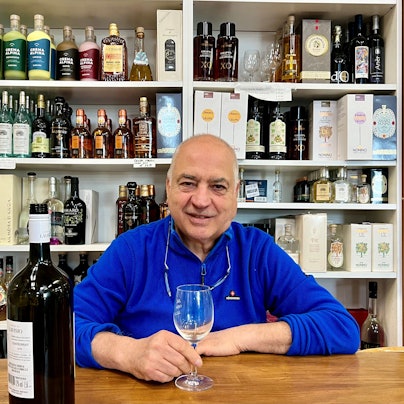 Mann mit einem Weinglas vor einem Spirituosenregal