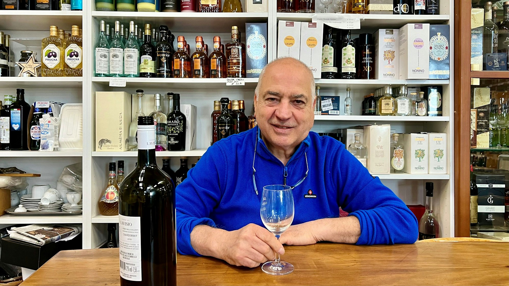 Mann mit einem Weinglas vor einem Spirituosenregal