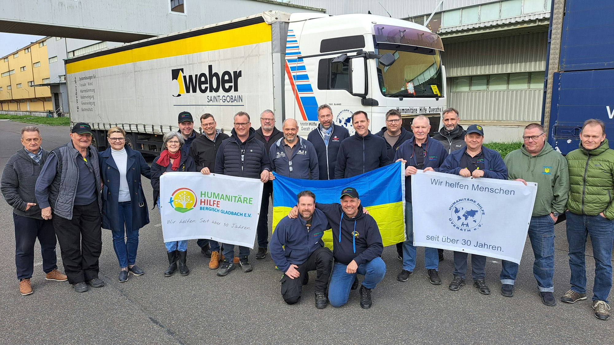 Fahrerinnen und Fahrer des Hilfskonvois der Humanitären Hilfe Overath und Bergisch Gladbach stehen vor 40-Tonner-Lkw des neunten Ukraine-Hilfskonvois der beiden bergischen Hilfsorganisationen.