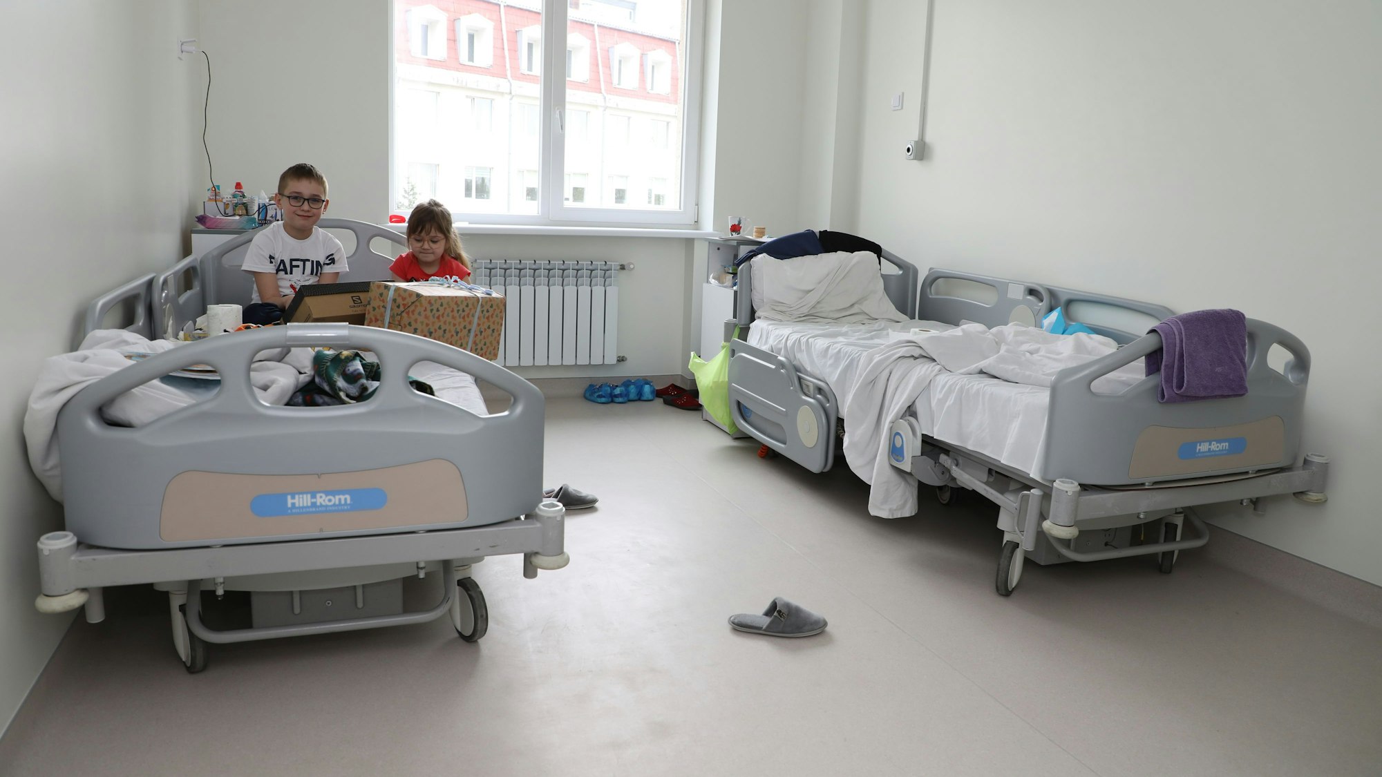 Zwei Kinder sitzen auf einem Krankenbett in der Kinderklinik Lviv.