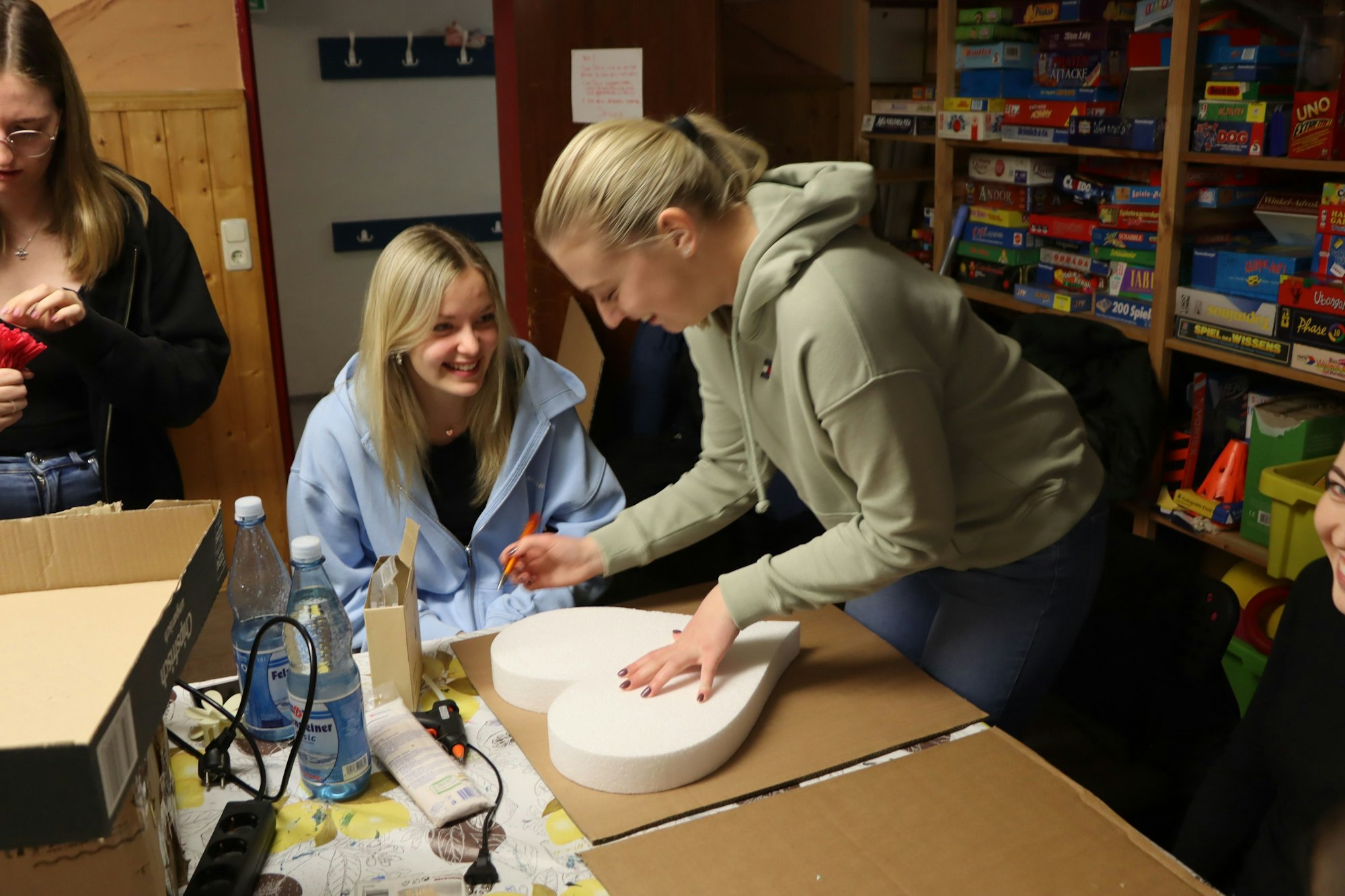 Das Bild zeigt zwei junge Frauen, die Maiherzen basteln.