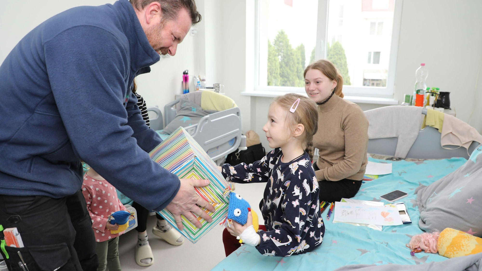 Thomas Migenda von der Humanitären Hilfe Overath überreicht einem Kind in der Kinderklinik Lviv ein Geschenk.