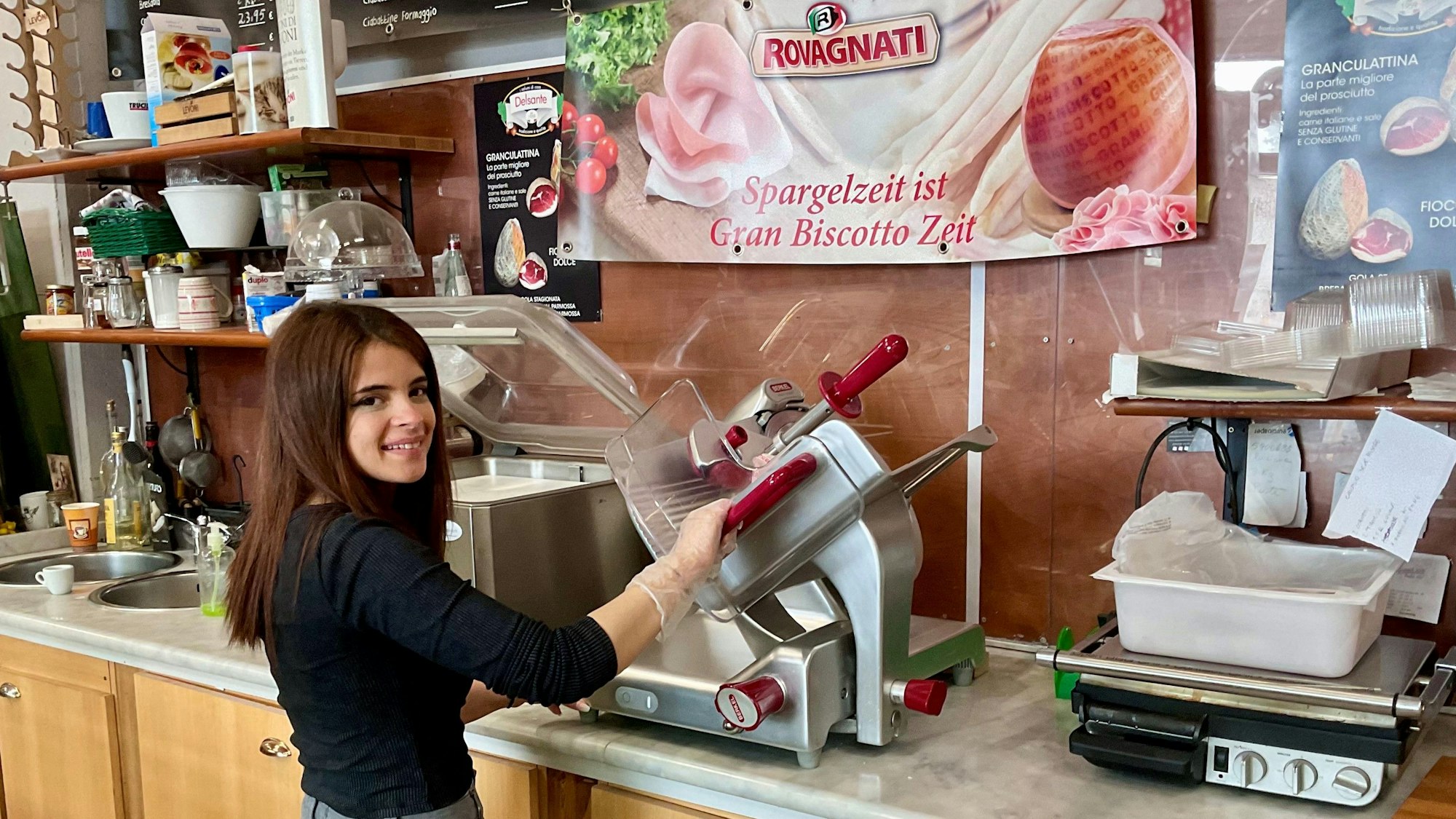 Junge Frau an der Aufschnittmaschine.