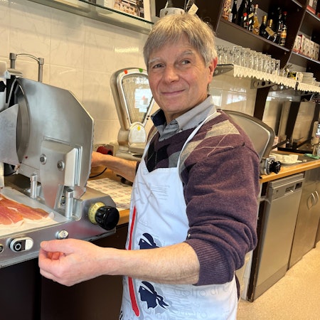 Mann an einer Aufschnittmaschine für Schinken