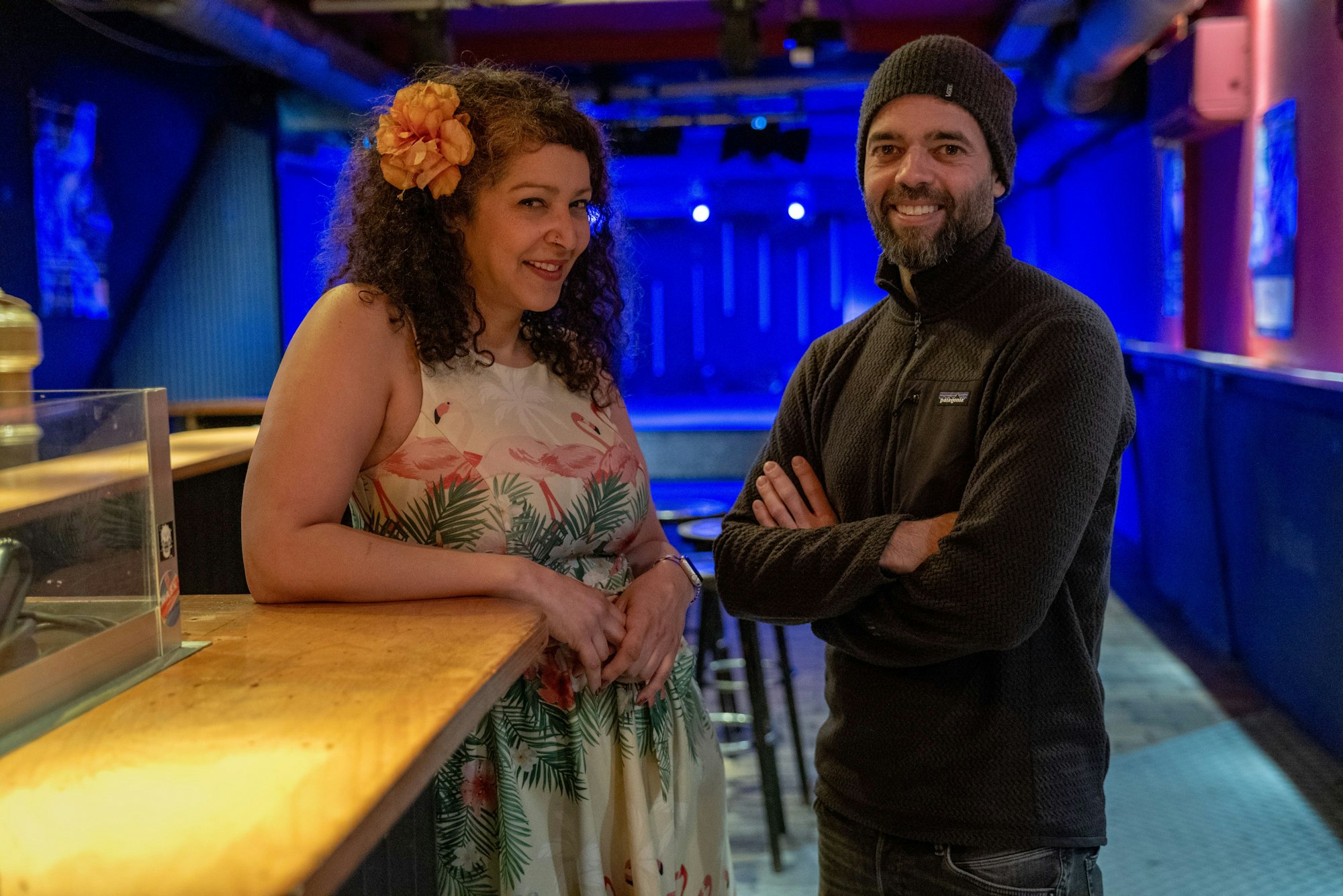 Zwei Menschen stehen in einem leeren Club an der Theke.