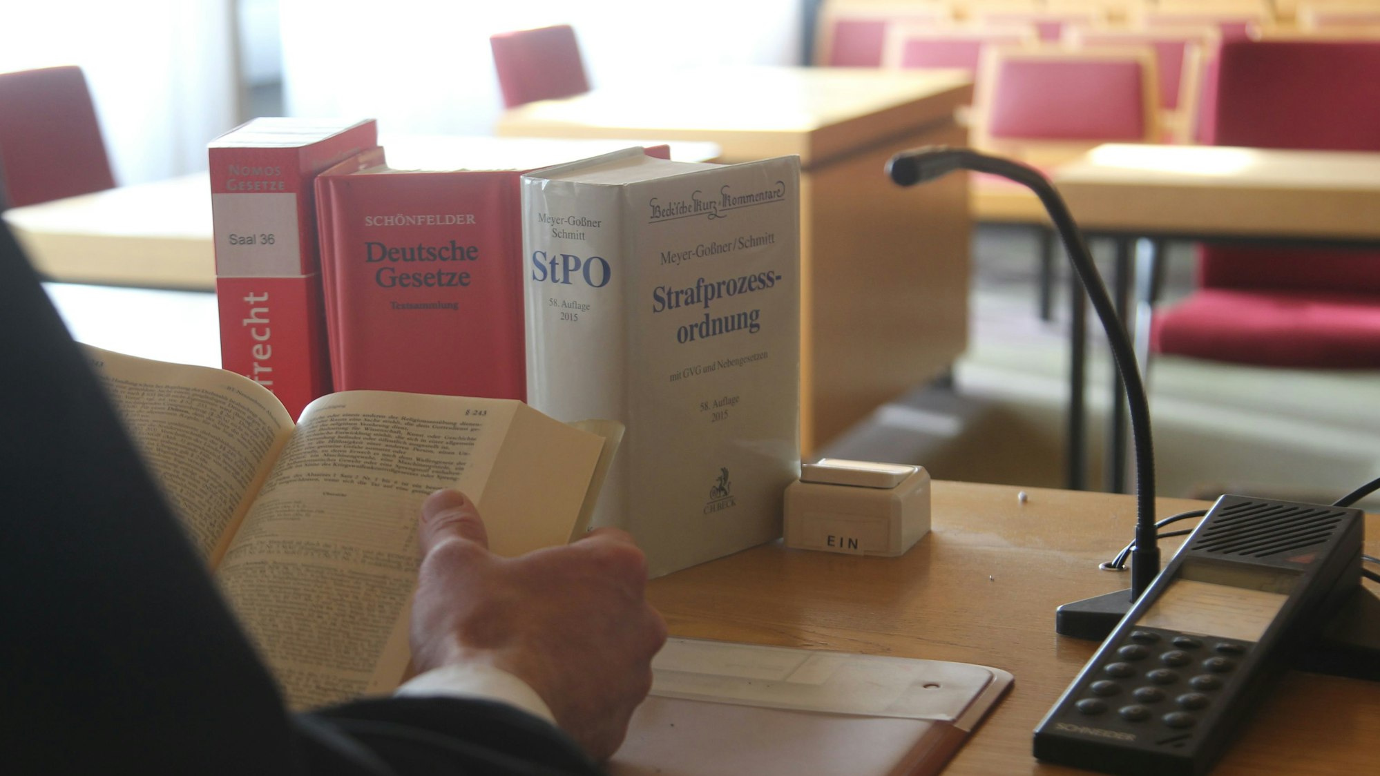 Gesetzesbücher neben einem Mikrofon in einem Gerichtssaal.