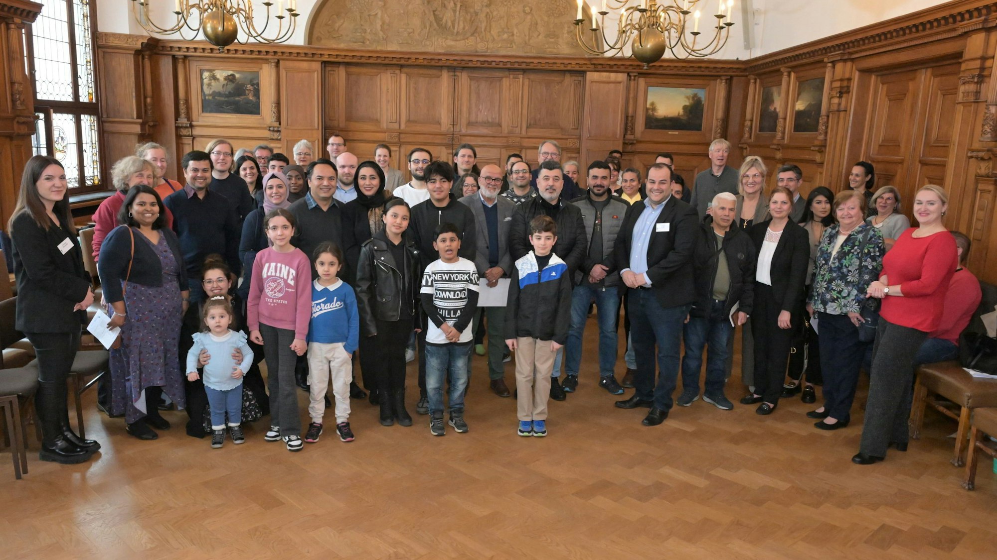 Hintereinander stehen die Gäste sowie Vertreter von Stadtverwaltung und Integrationsrat in Viererreihen.