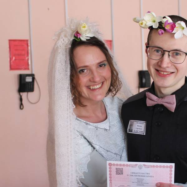 Evgenia Kulakova undViktor Filinkov, sie mit weißem Schleier, er mit Blumenkranz im Haar, bei der Hochzeit im Gefängnis. Beide lachen.