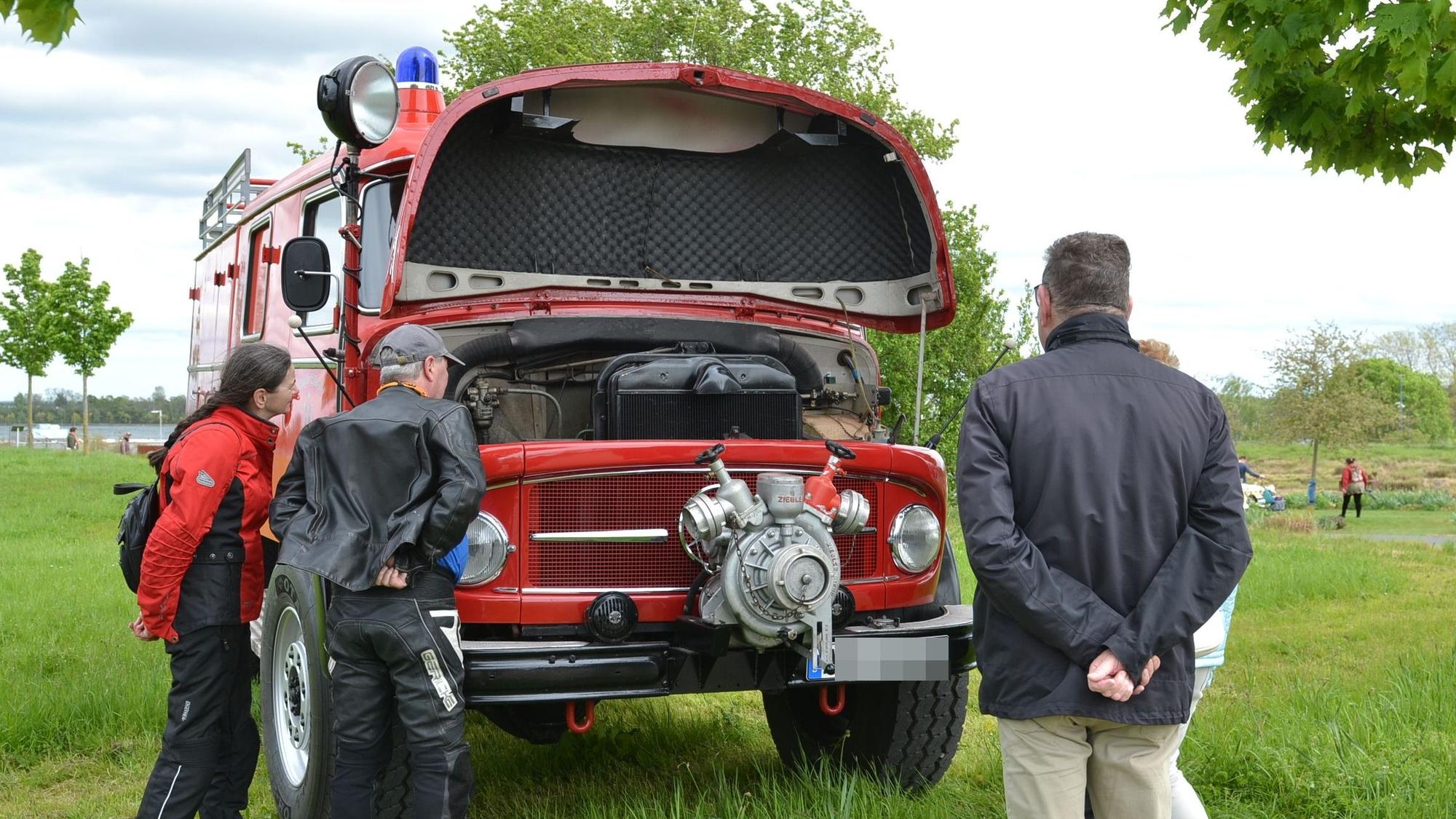 Ein Paar schaut in den Motorraum eines alten Feuerwehrautos.