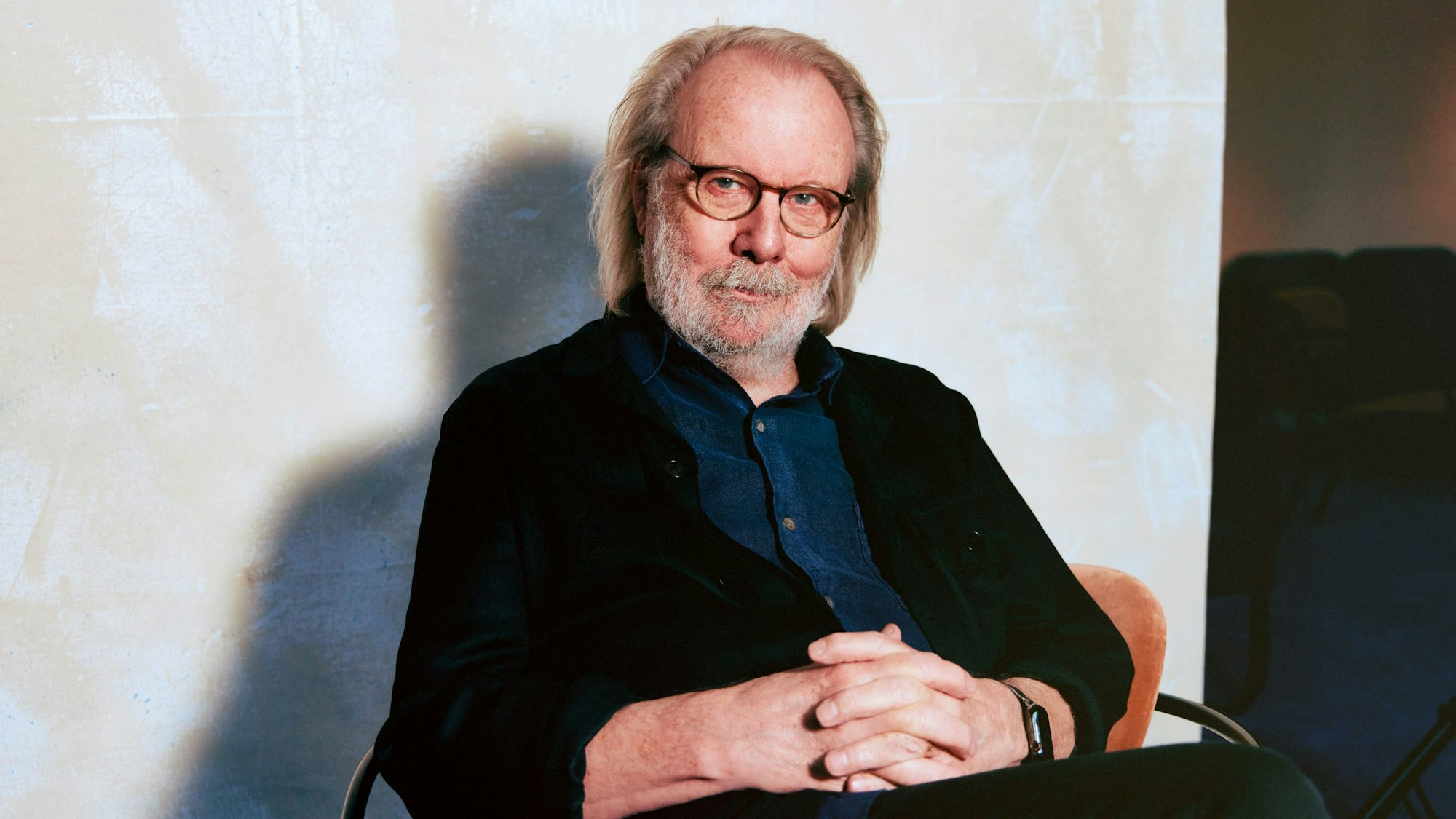 Abba-Star Benny Andersson sitzt auf einem Stuhl und sieht in die Kamera.