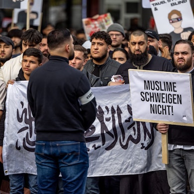 Teilnehmer einer Islamisten-Demo in Hamburg halten am Samstag ein Plakat mit der Aufschrift ·Muslime schweigen nicht in die Höhe.