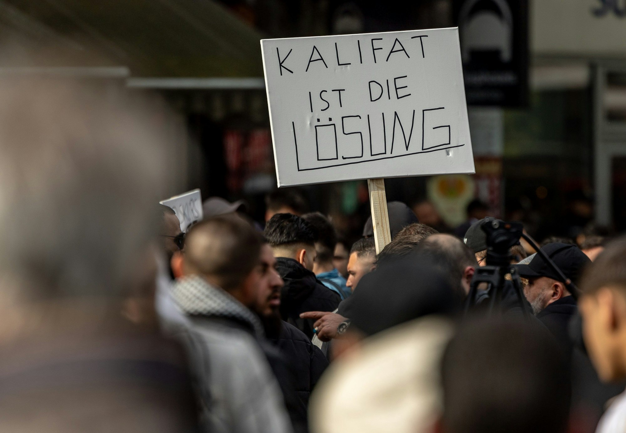 27.04.2024, Hamburg: Teilnehmer einer Islamisten-Demo halten ein Plakat mit der Aufschrift ·Kalifat ist die Lösung· in die Höhe. Foto: Axel Heimken/dpa +++ dpa-Bildfunk +++