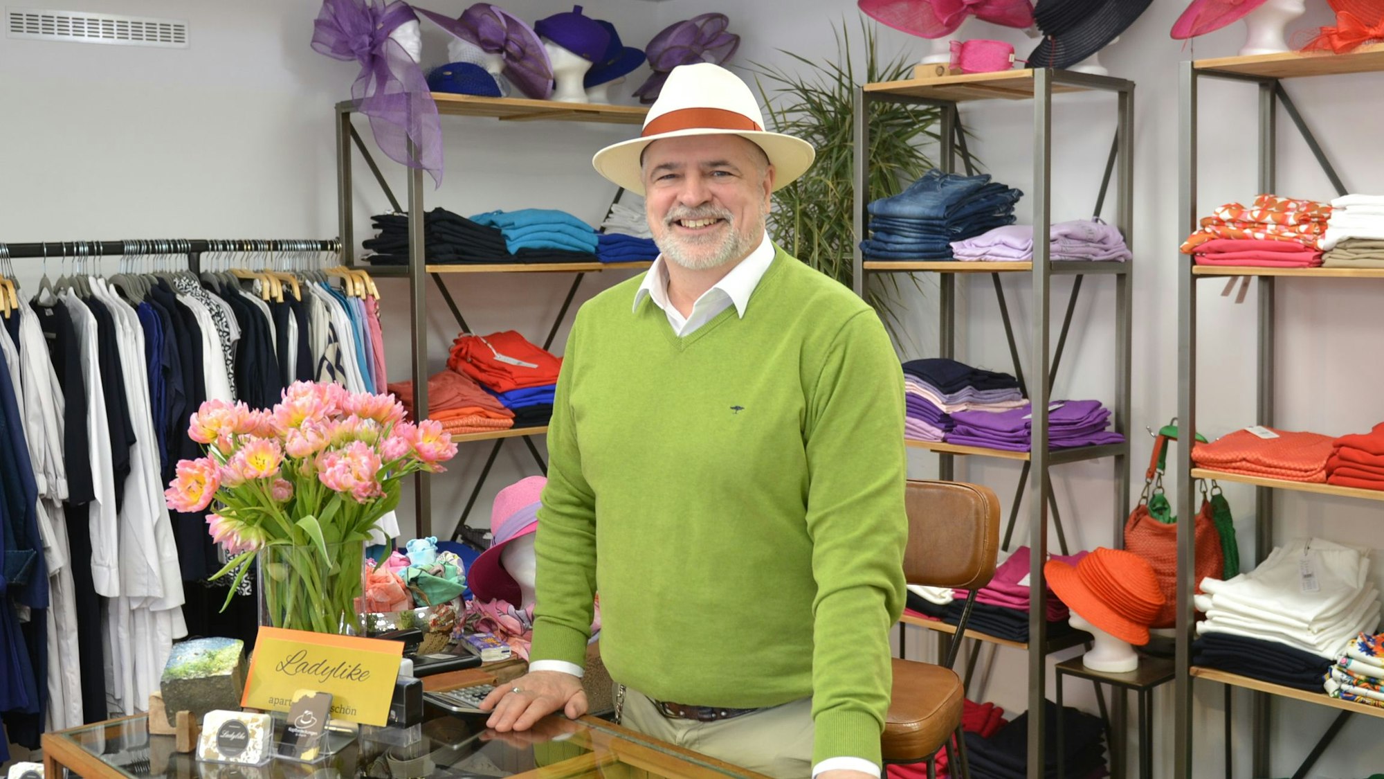 Norbert Hollender steht zwischen Regalen mit Hüten und Kleidung.