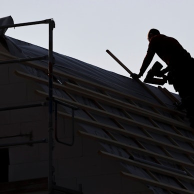 Ein Dachdecker arbeitet auf einem Einfamilienhaus.