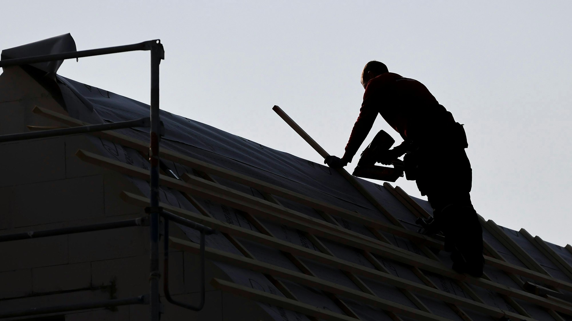 Ein Dachdecker arbeitet auf einem Einfamilienhaus.