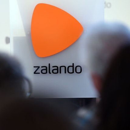 Das Logo des Onlineversandhändlers Zalando ist an einer Glasfassade zu sehen. Markant ist über dem Schriftzug ein orangefarbenes Dreieck zu erkennen.