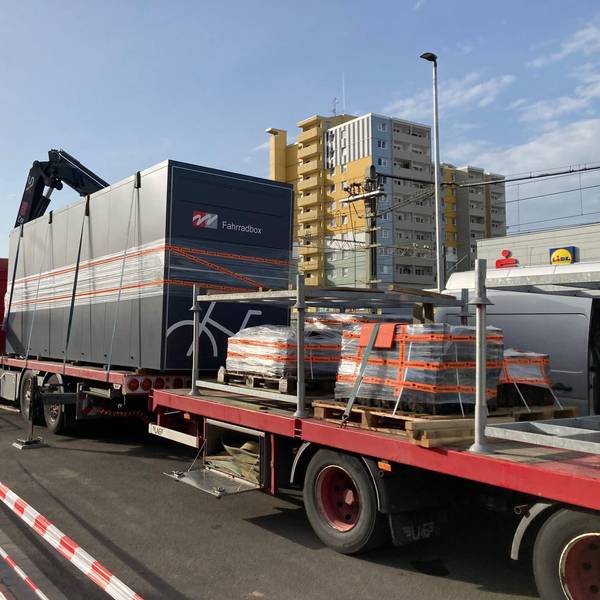 Auf dem Foto sind Schwertransporter mit den Fahrradboxen auf der Ladefläche zu sehen.