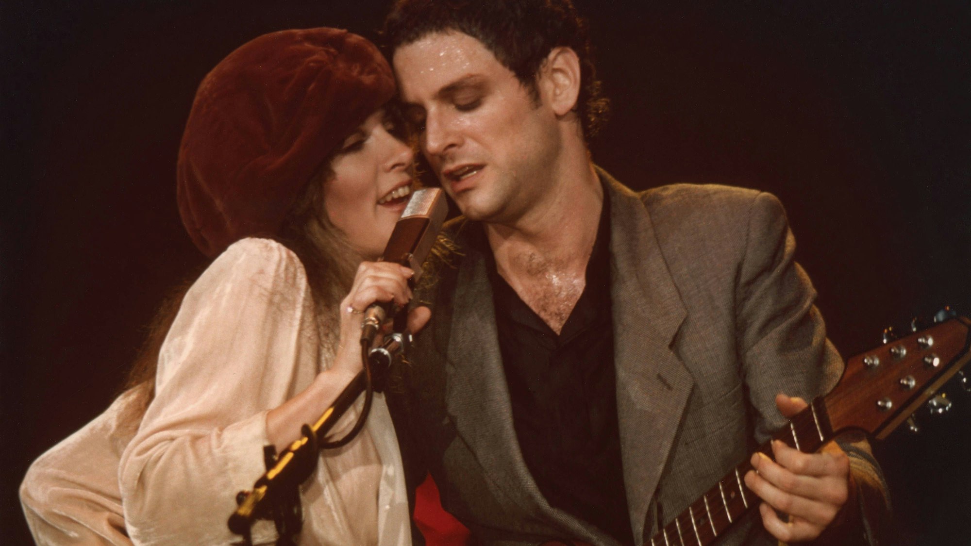 Stevie Nicks und Lindsey Buckingham von der Band Fleetwood Mac teilen sich auf der Bühne des Civic Center in Providence, Rhode Island ein Mikrofon. Die Aufnahmen stammt aus den 1970er Jahren.