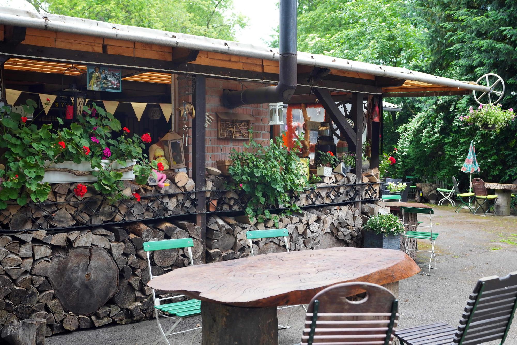 Der Biergarten im Steinbud "Zur grünen Oase", Holztische, Stühle und Mauern.