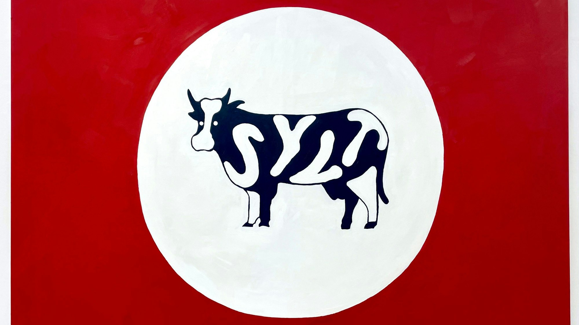 Eine Kuh mit dem Schriftzug Sylt steht in einem weißen Kreis vor einem roten Hintergrund.