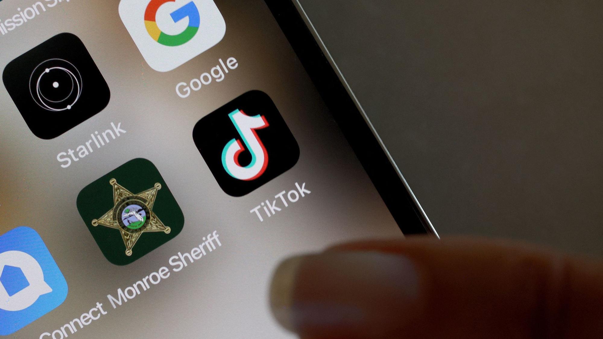 Ein Finger zeigt auf ein TikTok-Icon auf einem Handy.