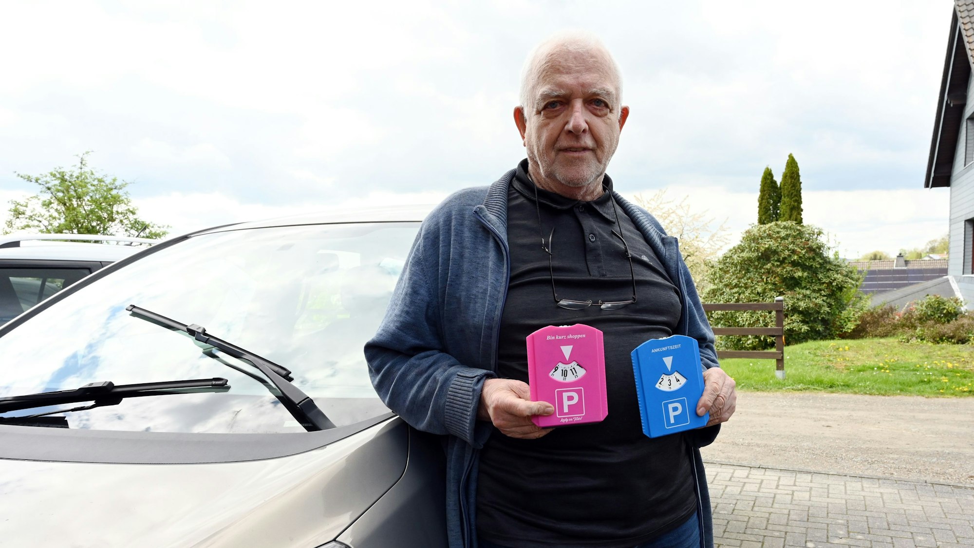 Foto eines Mannes, der eine pinke und eine blaue Parkscheibe in den Händen hält.