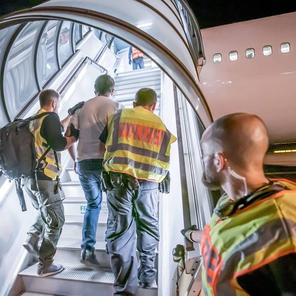 Polizeibeamte begleiten einen Afghanen auf dem Flughafen Leipzig-Halle in ein Charterflugzeug.