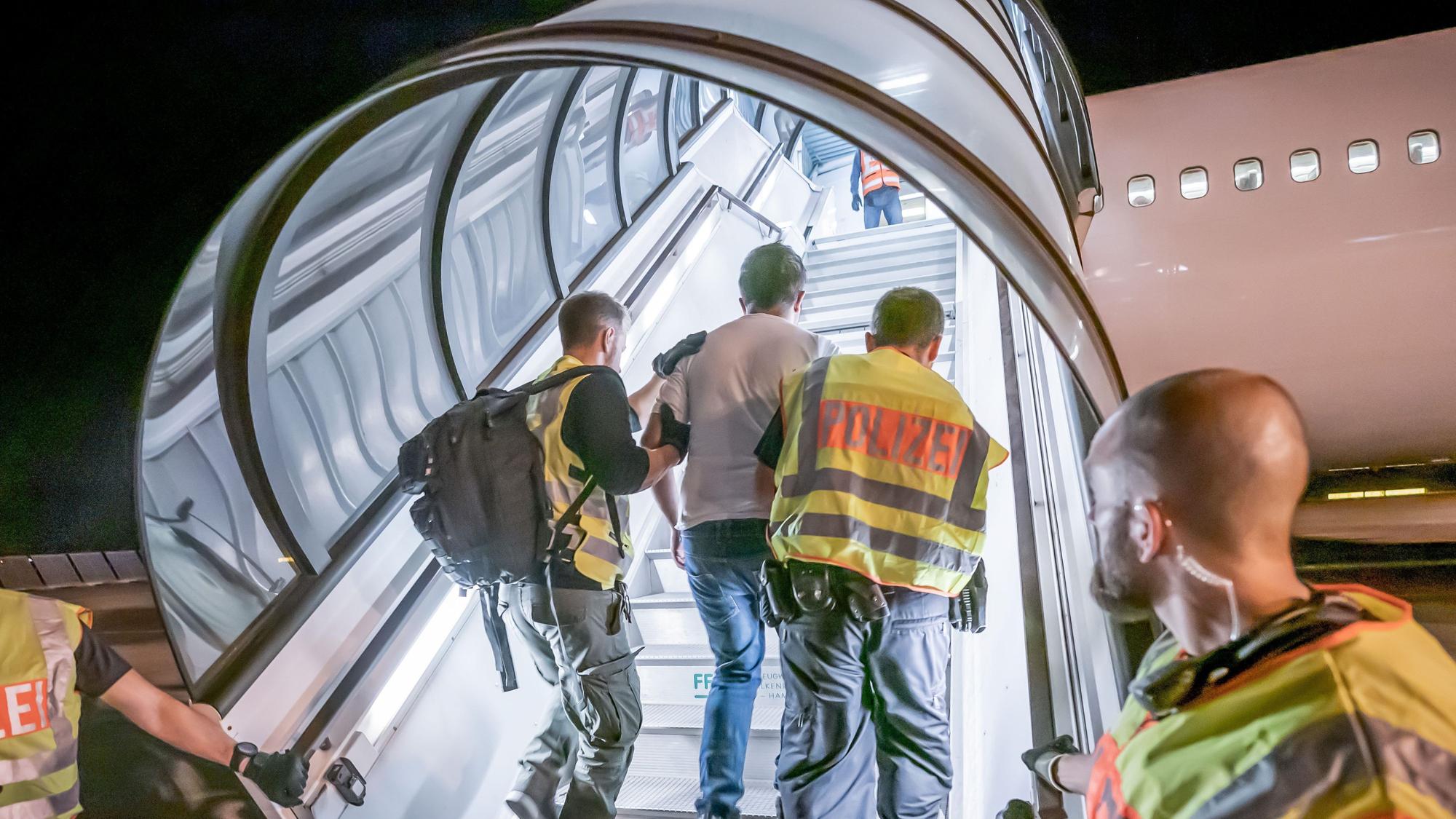Polizeibeamte begleiten einen Afghanen zur Abschiebung in ein Charterflugzeug.