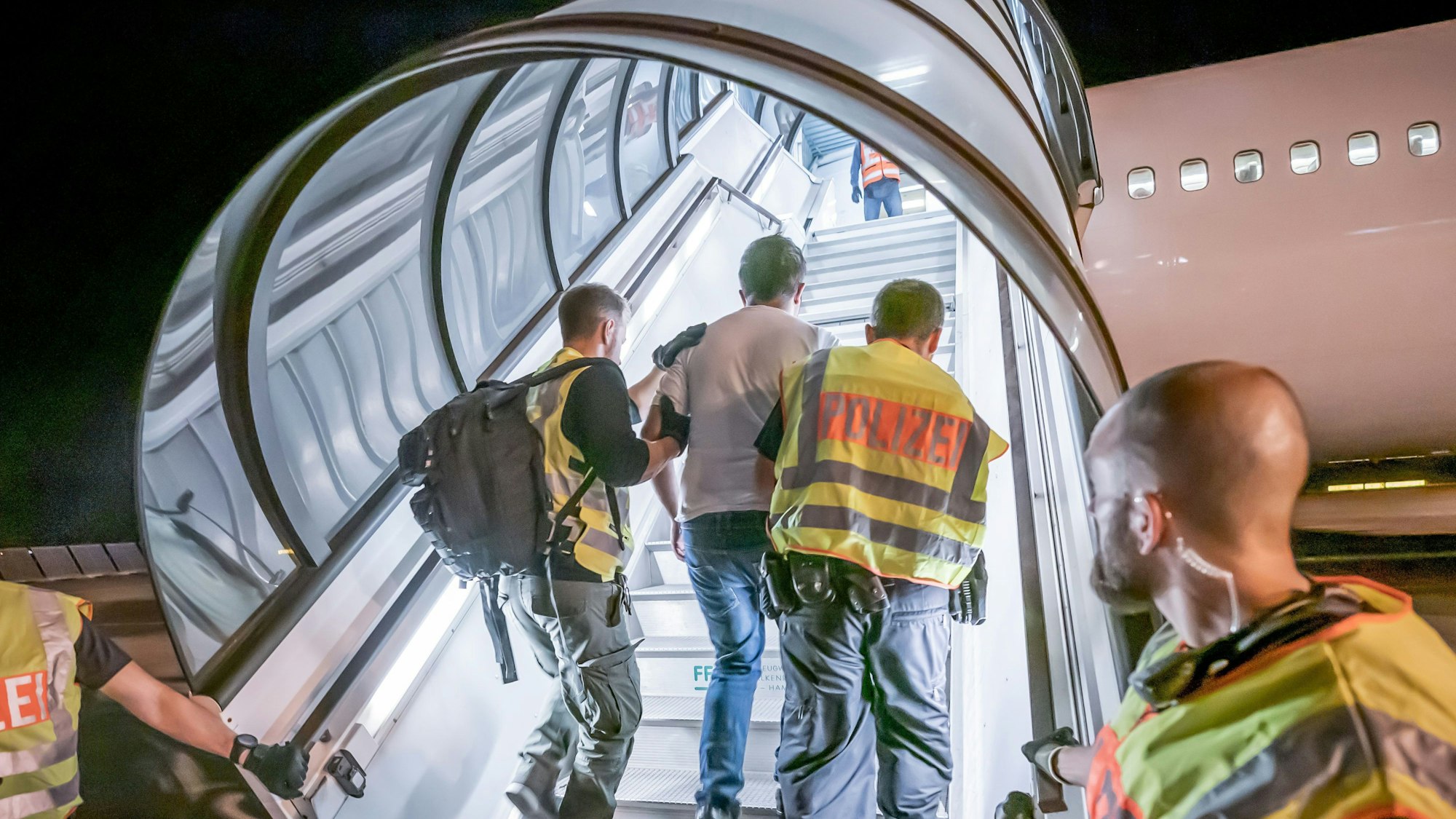 Polizeibeamte begleiten einen abgeschobenen Asylbewerber ins Flugzeug.