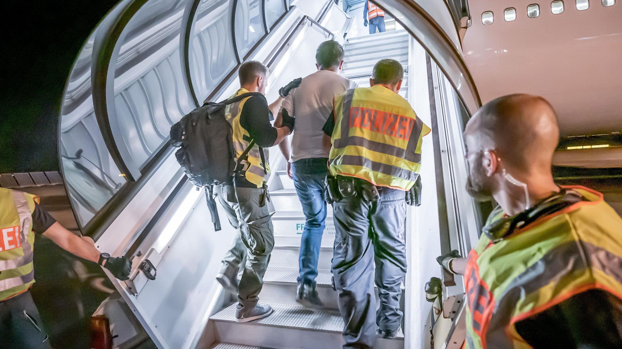 Polizeibeamte begleiten einen Afghanen zur Abschiebung in ein Charterflugzeug.