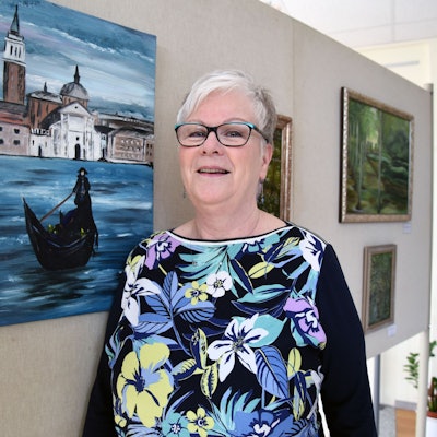 Die Künstlerin Gabriele Mückl steht vor einem Bild.